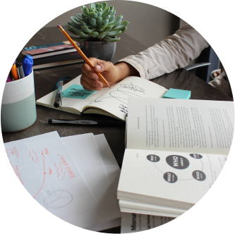 Person holding writing on a notebook while reading  a book